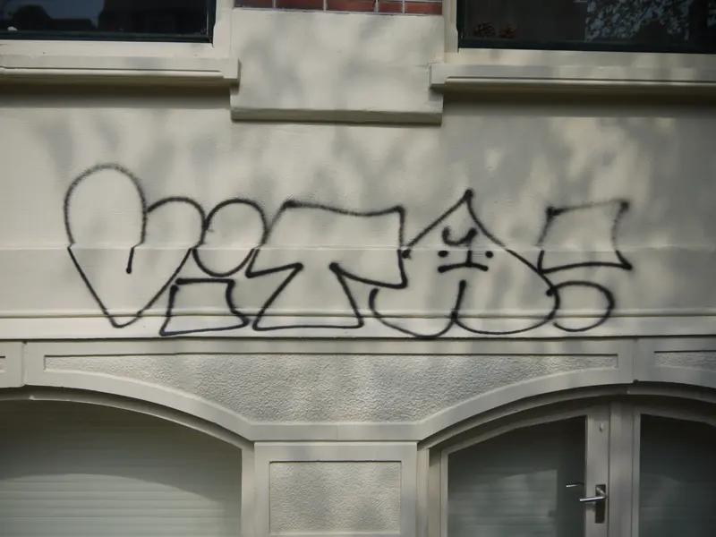 Tagging med svart spraymaling på en lys fasade